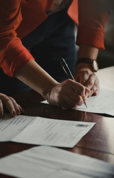 person in orange long sleeve shirt writing on white paper